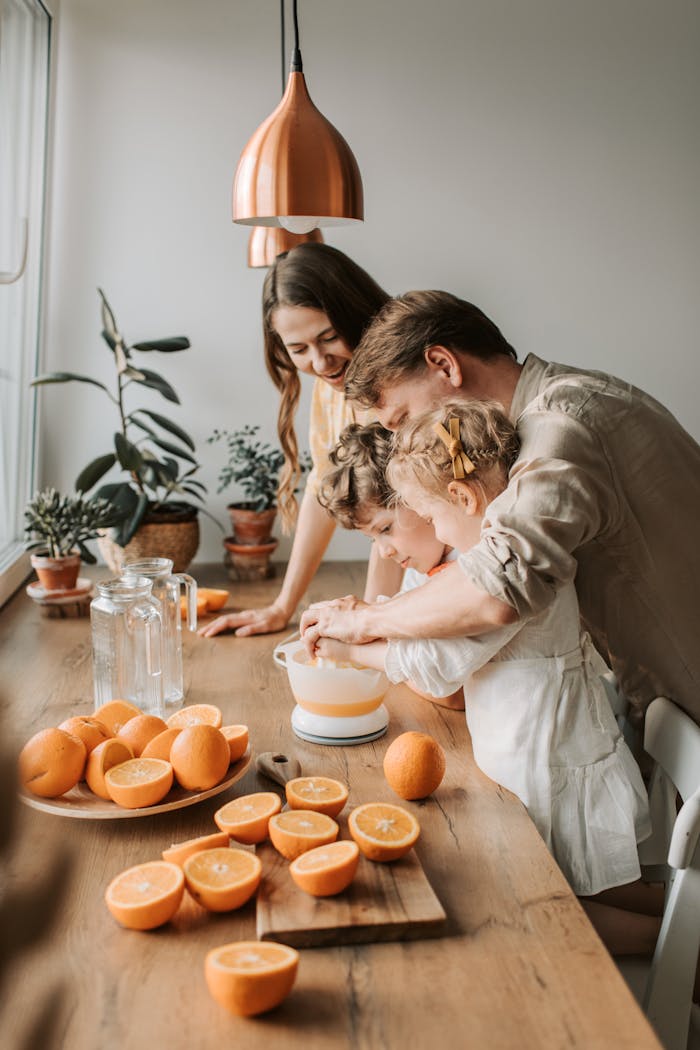 gallery-2 A family enjoys squeezing fresh orange juice together in a cozy kitchen setting filled with natural light.